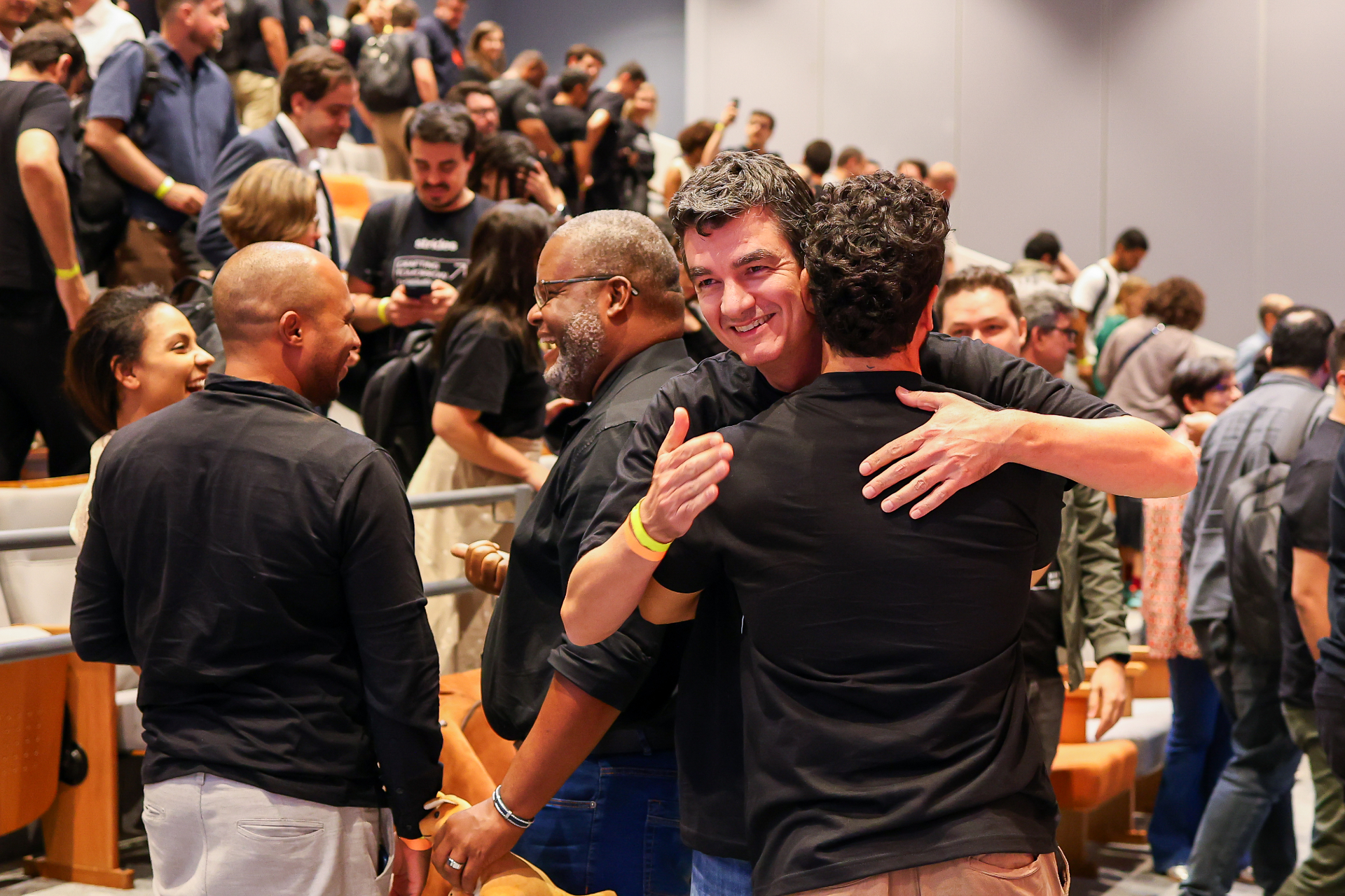 Dois líderes se abraçam em meio à plateia do Tech Leadership Summit da Strides em São Paulo